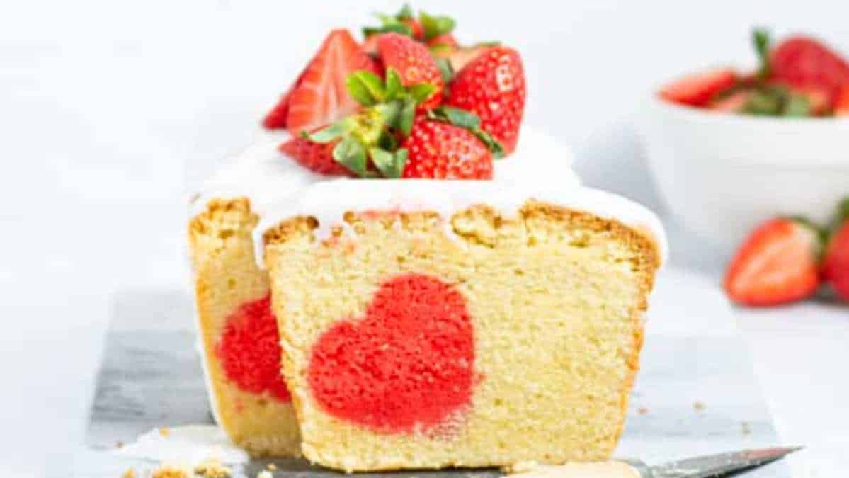 A slice of strawberry cake with a heart cut out of it.