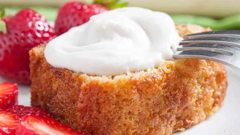 A fork on a piece of cake with whipped cream.