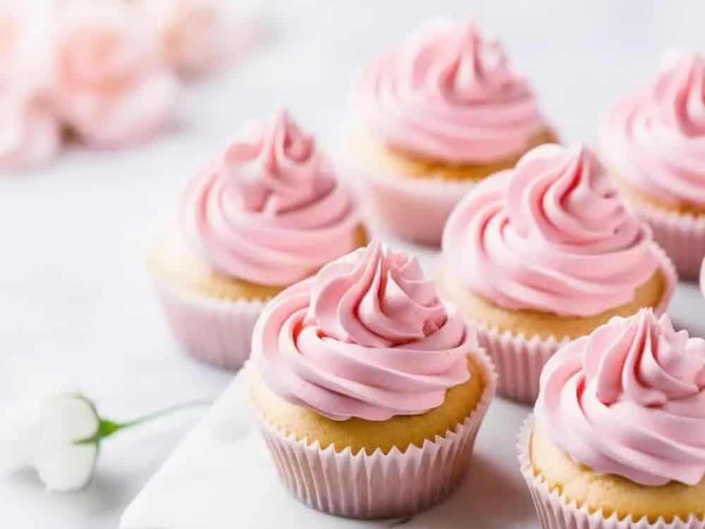 Pink frosted cupcakes on a marble plate.