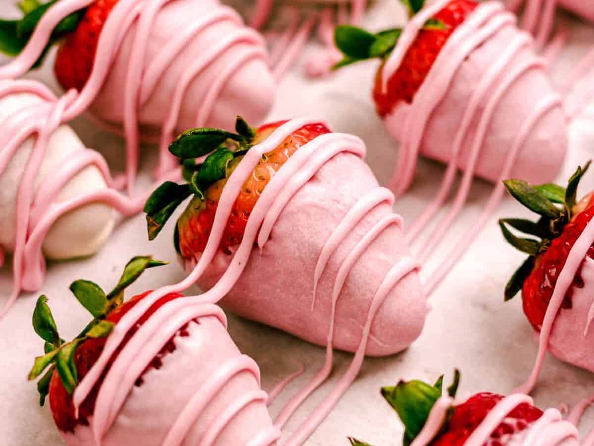 A bunch of strawberries covered in pink icing.