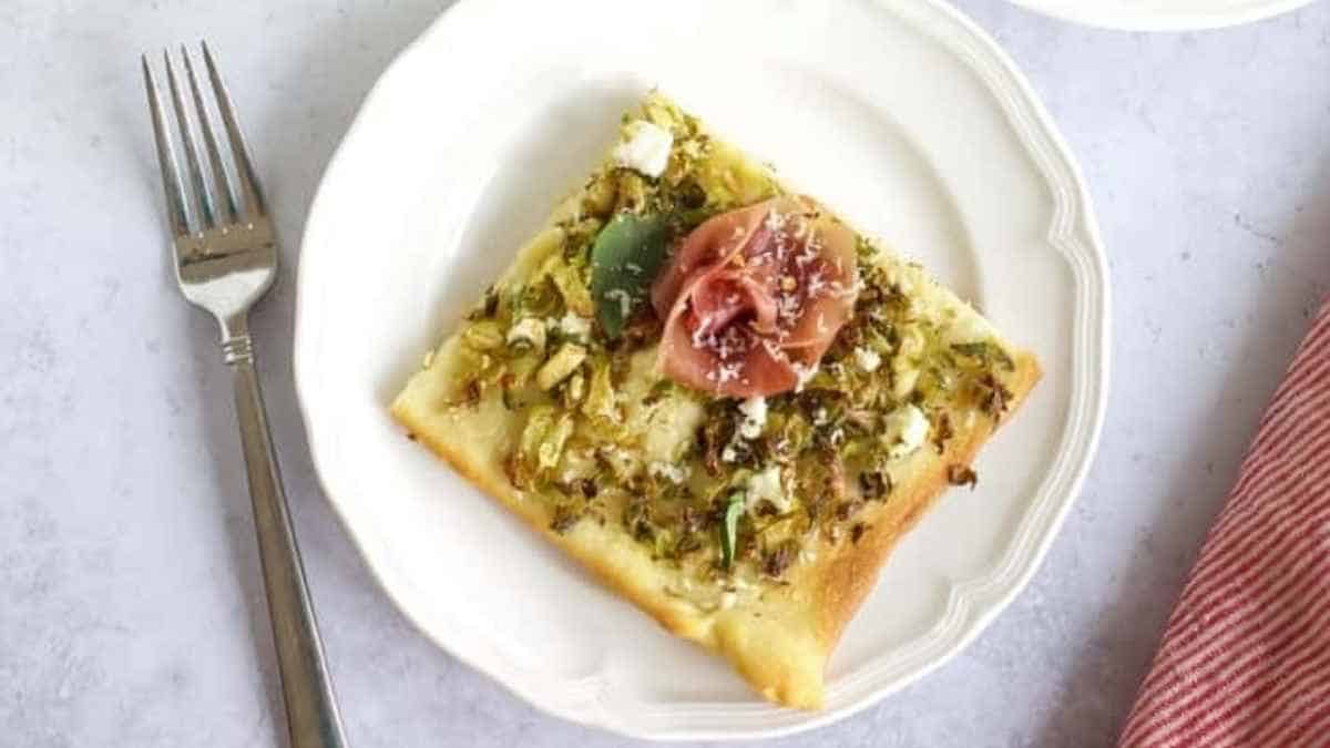 A slice of pizza with artichoke and tomato on a plate.