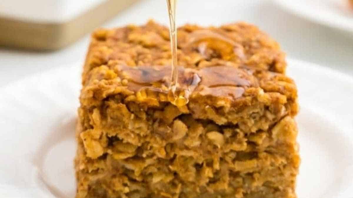 A slice of oatmeal cake being drizzled with honey.