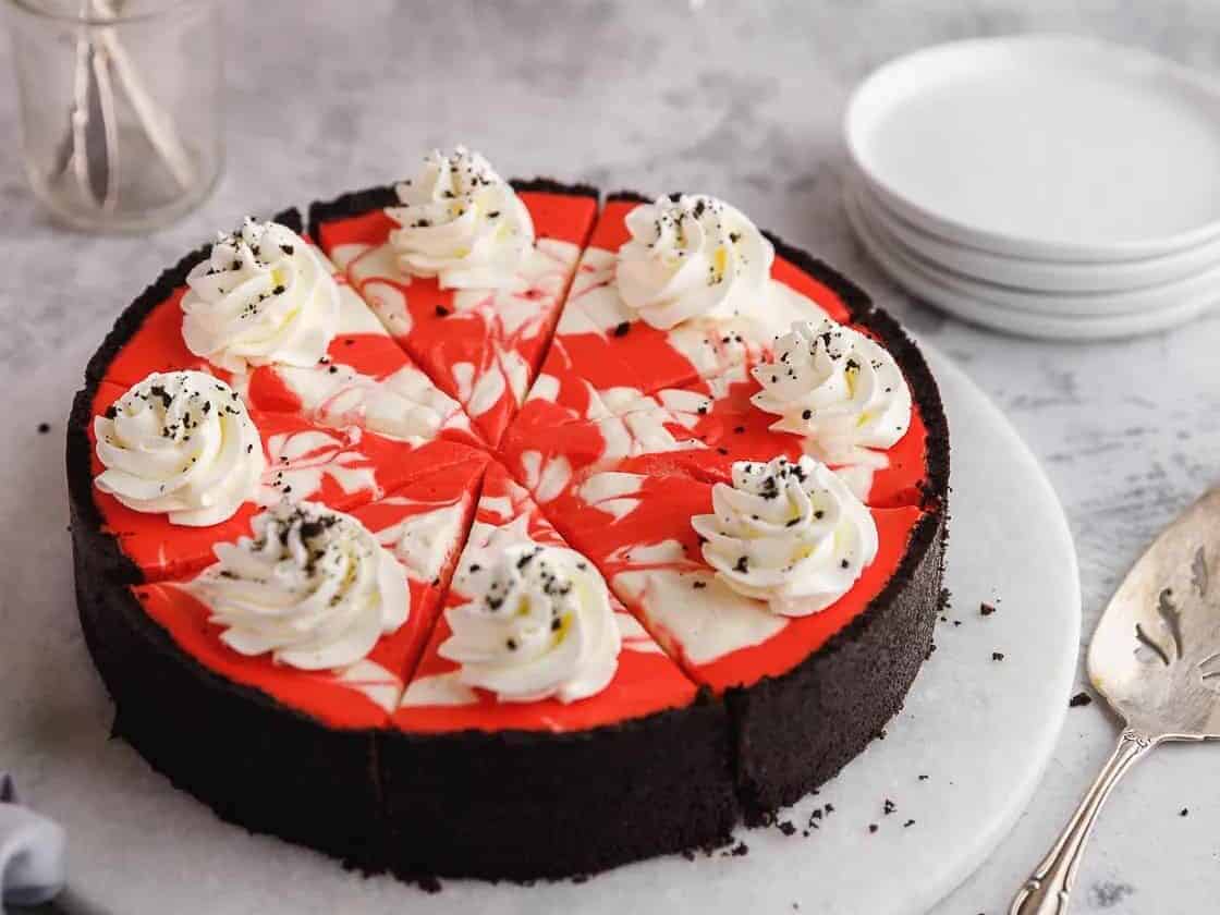 A red and white cheesecake on a white plate.