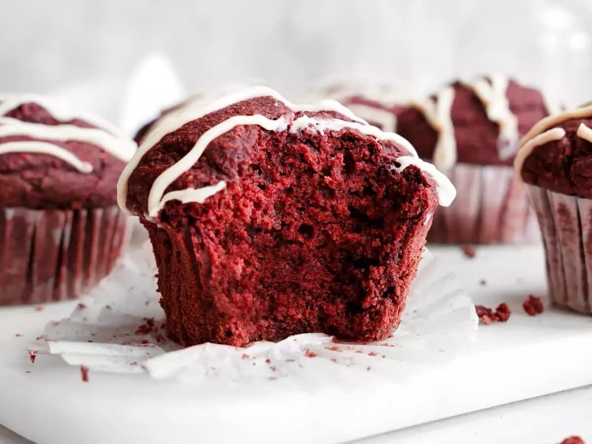 Red velvet muffins with a bite taken out of them.