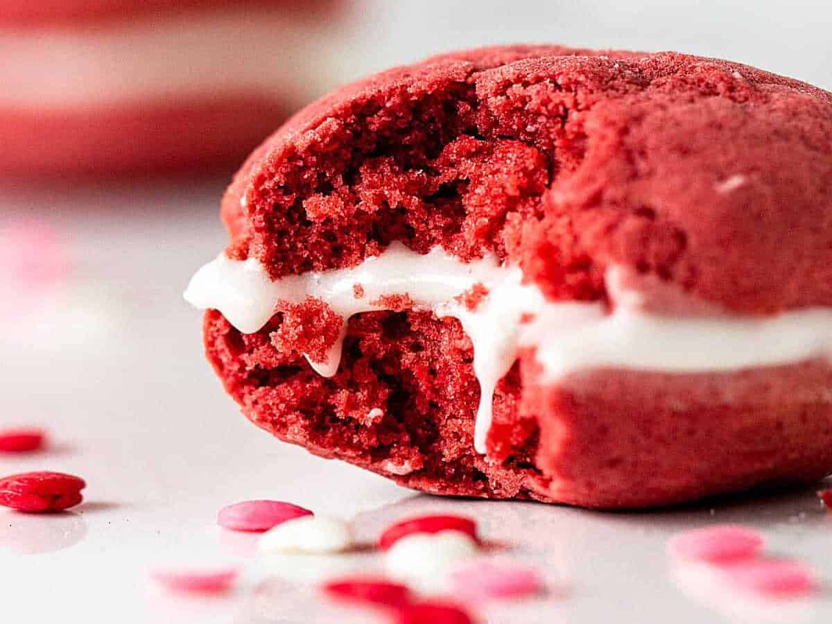 A red velvet cookie with a bite taken out of it.