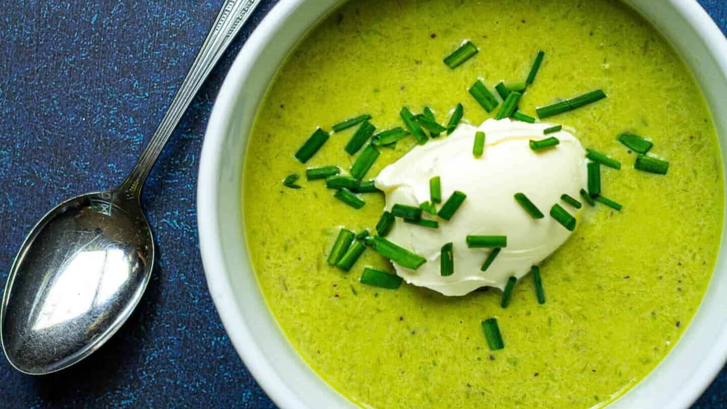 A bowl of green asparagus soup with sour cream and chives.