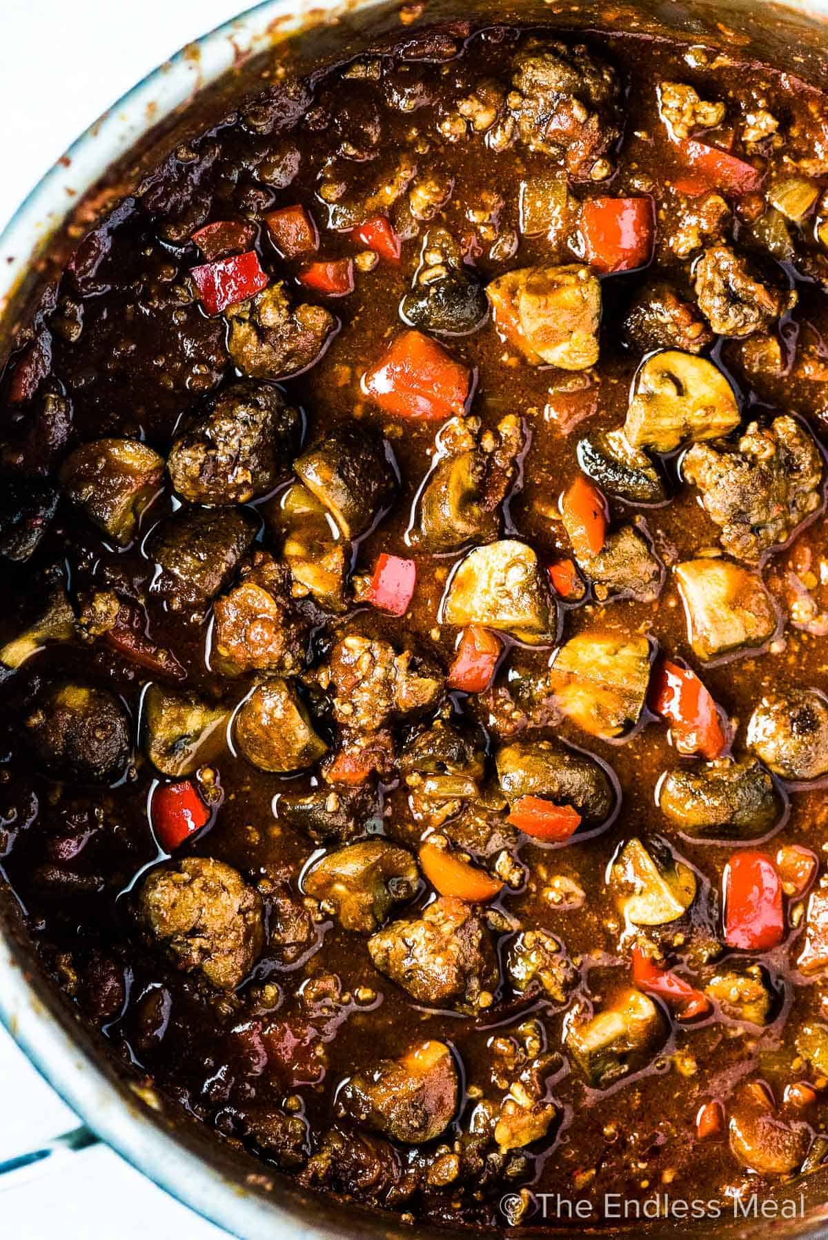 A hearty pot of sausage stew with a medley of vegetables simmering in it.