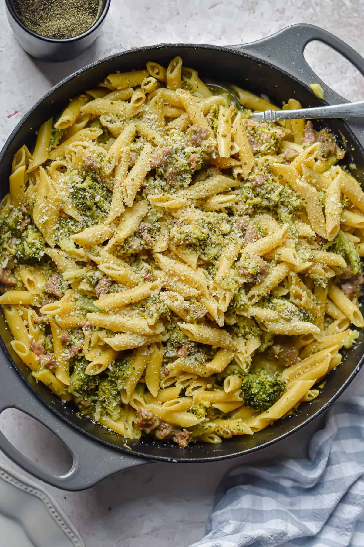 A skillet filled with sausage and broccoli pasta.