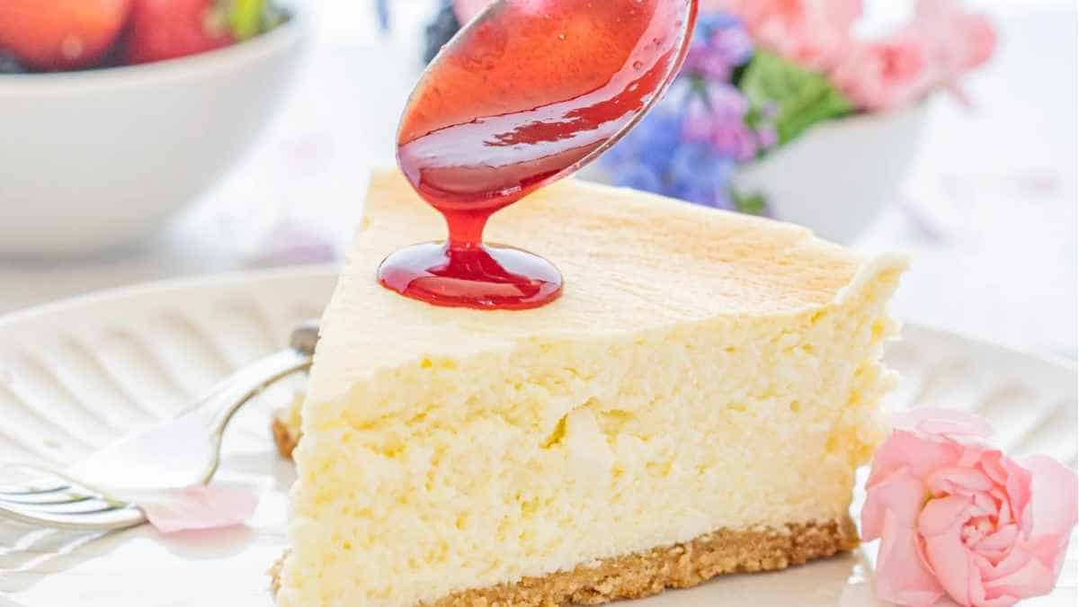 A slice of cheesecake with strawberry sauce on a plate.