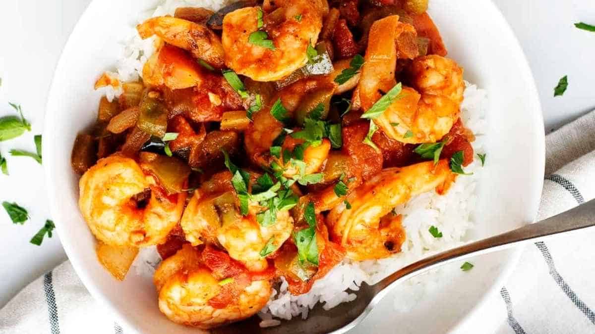 Shrimp and rice in a white bowl with a spoon.