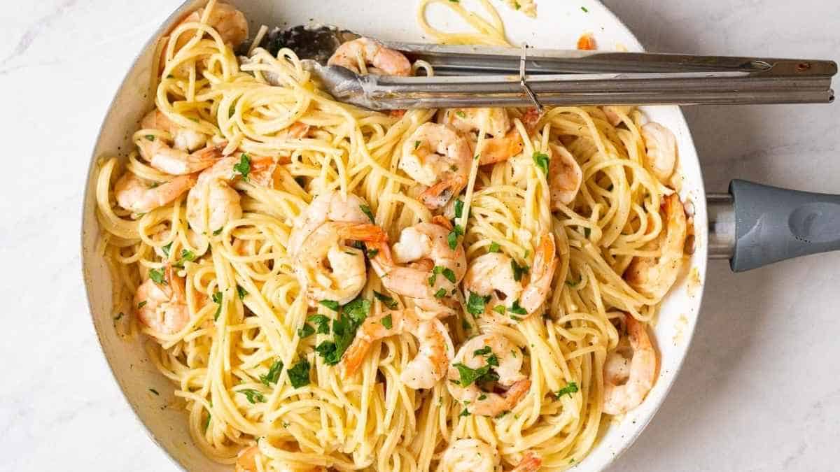 Shrimp and pasta in a pan with a fork.