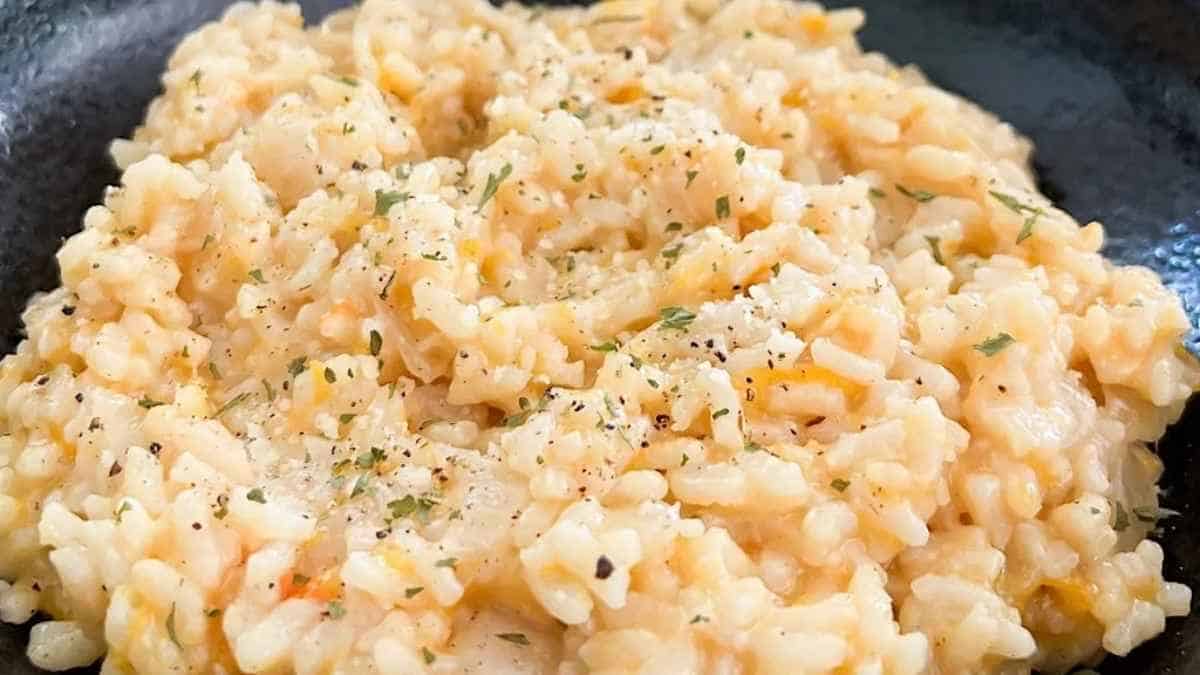 Risotto in a black skillet with herbs.