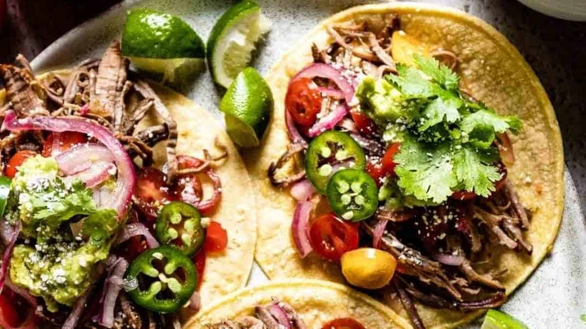 Two tacos with meat and vegetables on a plate.