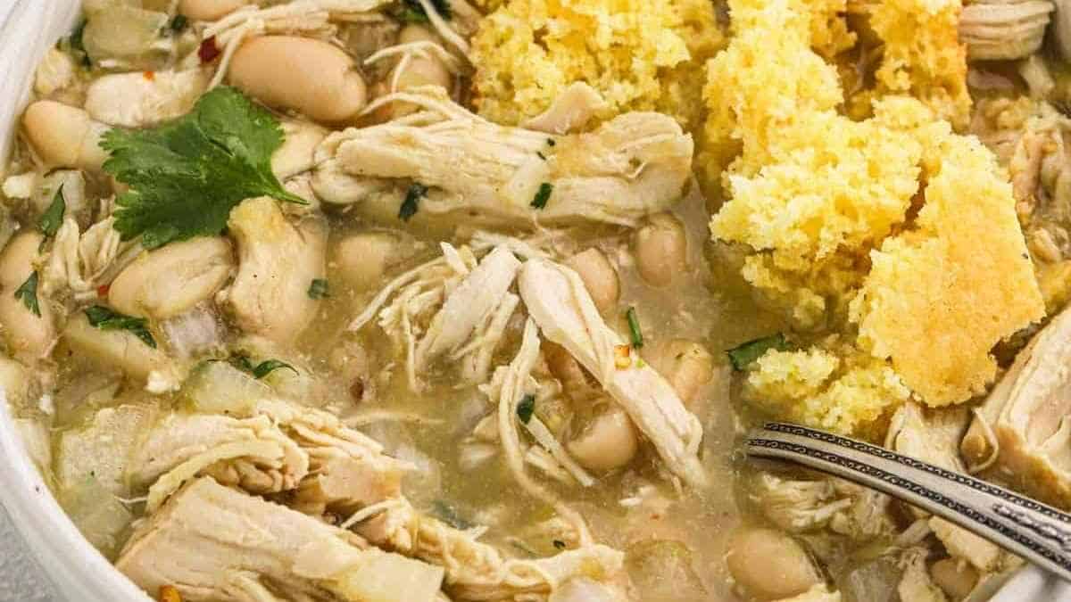 Chicken and white bean stew in a white bowl.
