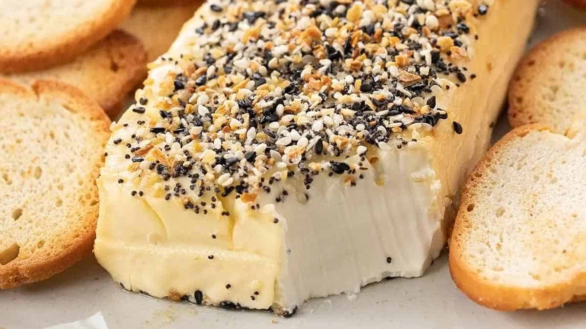 A slice of cheese with sesame seeds and crackers.
