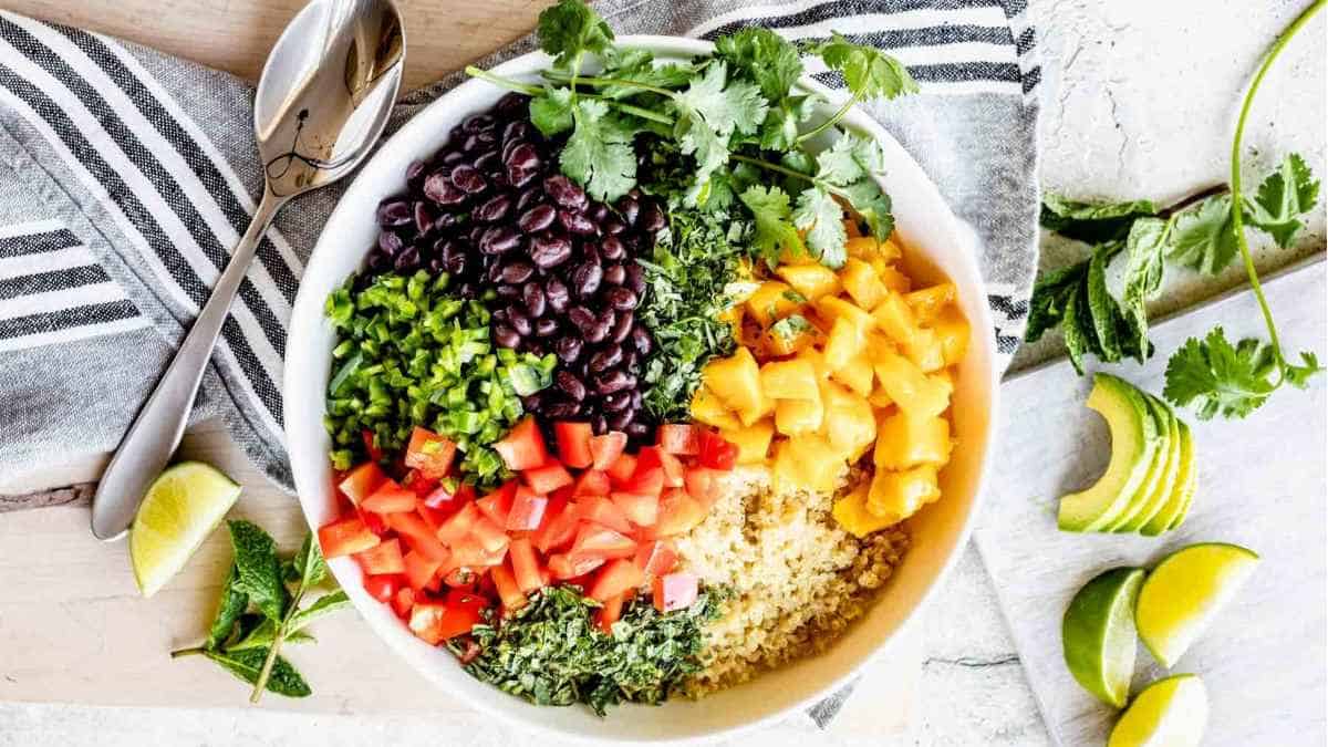 A bowl of quinoa salad with black beans, corn, tomatoes and avocados.