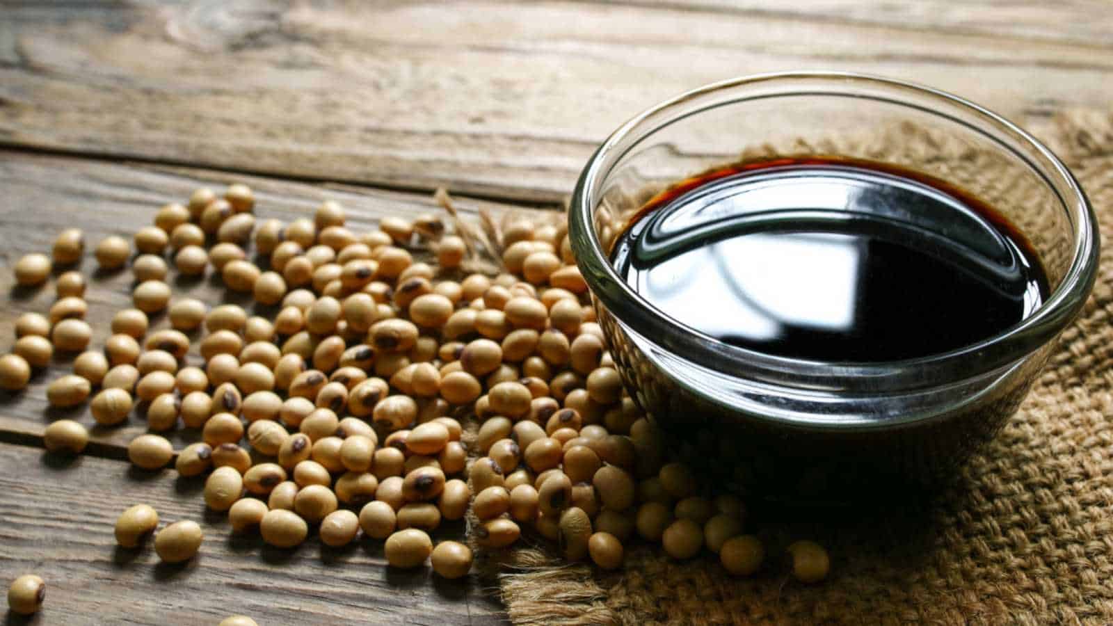 Soy sauce and soybeans on a wooden table.