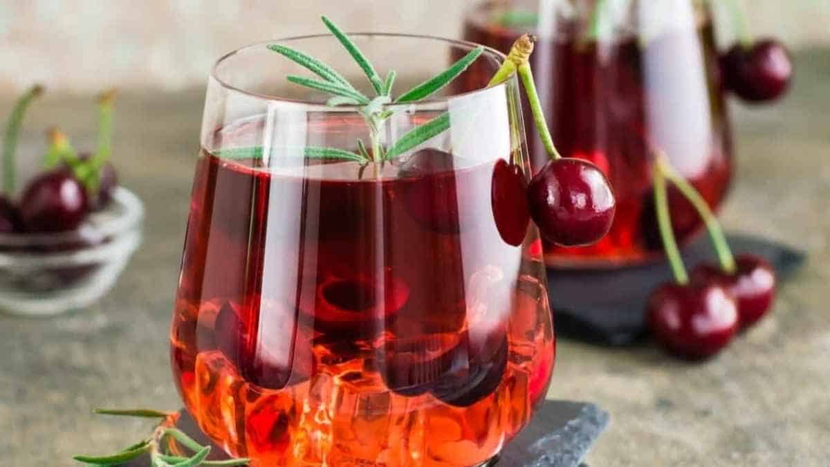 Cherries in a glass with rosemary sprigs.
