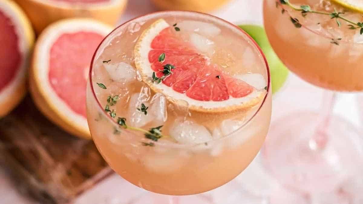 Two glasses of grapefruit juice with a slice of grapefruit.