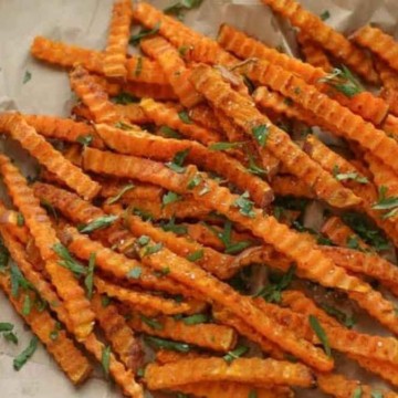 A plate of sweet potato fries with a dipping sauce.