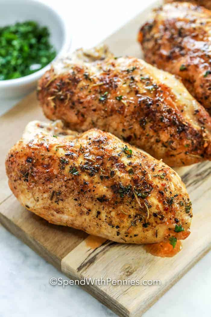 Bone-in chicken breasts on a wooden cutting board.
