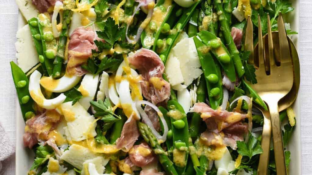 Ham and asparagus salad on a white plate.