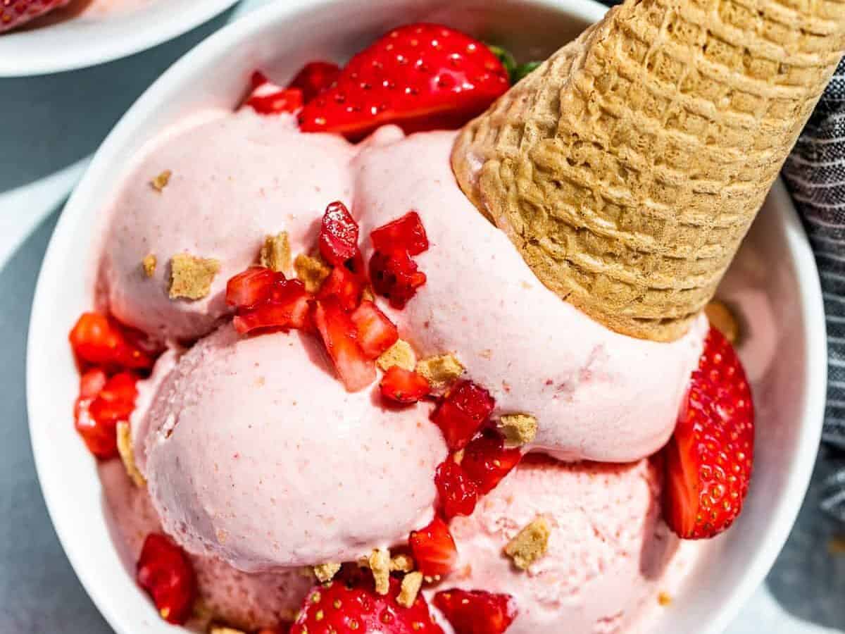 Strawberry ice cream in a bowl with a cone.