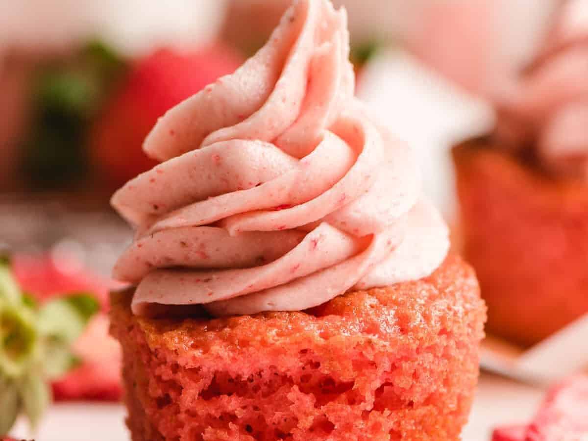 Strawberry cupcakes topped with whipped cream and strawberries.