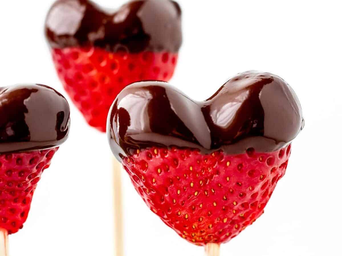 Three strawberry heart shaped lollipops on a stick.