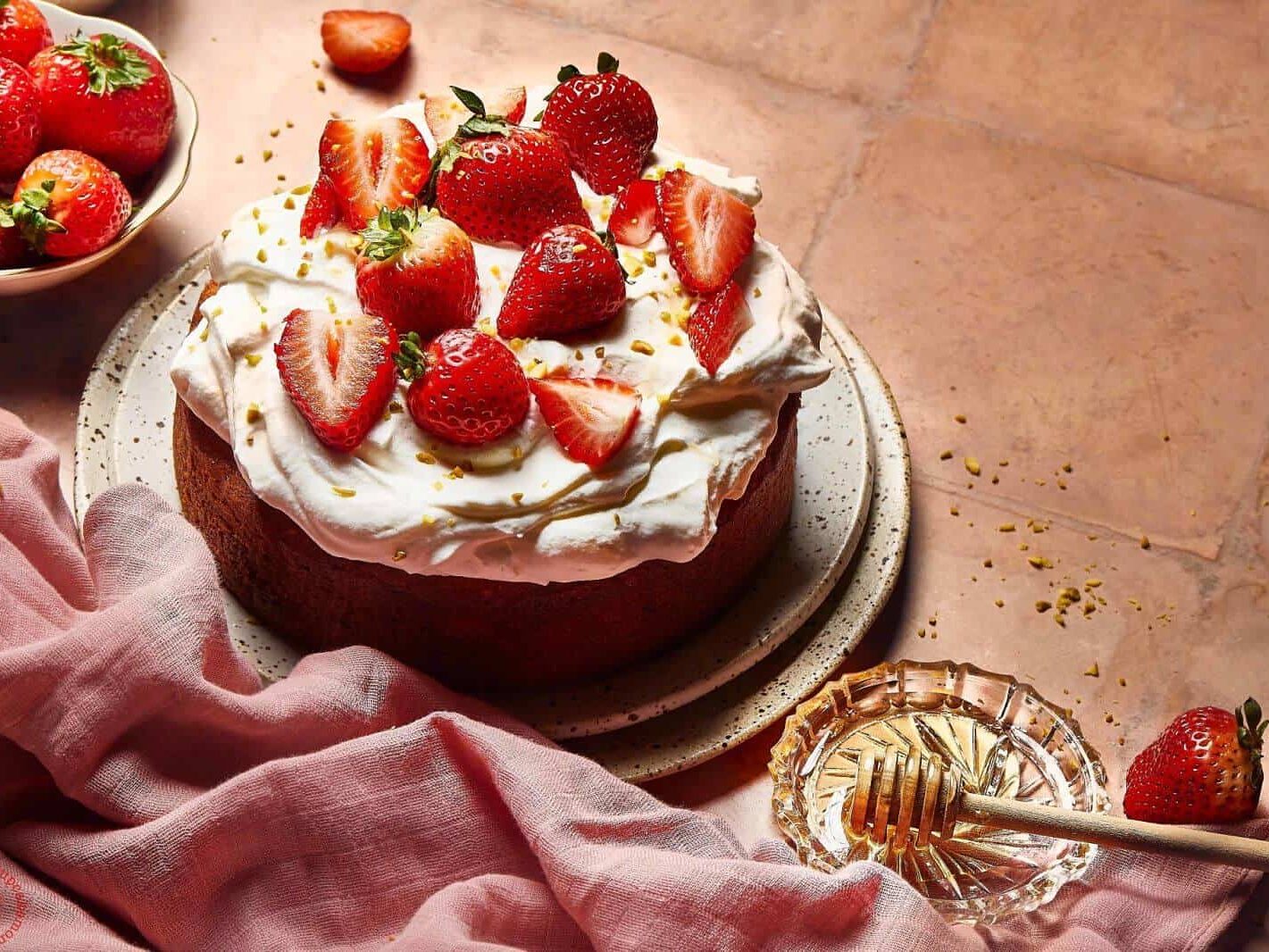 A cake with strawberries and whipped cream on a table.