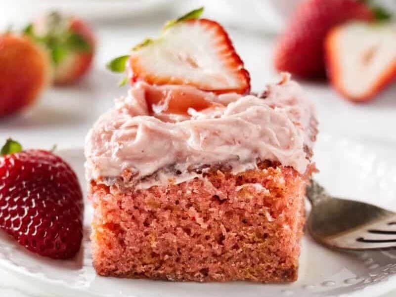 A slice of strawberry cake on a plate with a fork.