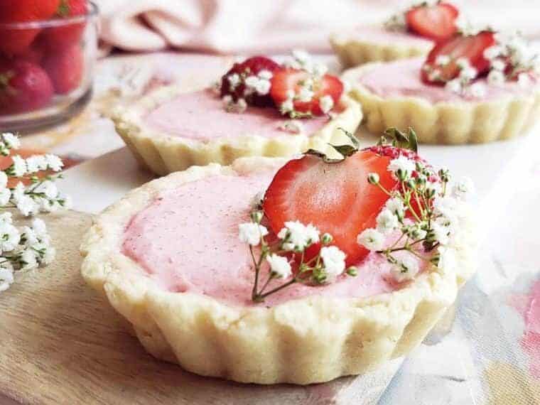 Strawberry tarts on a wooden cutting board with baby's breath.