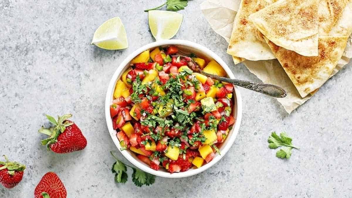 A bowl of salsa with strawberries and tortilla chips.