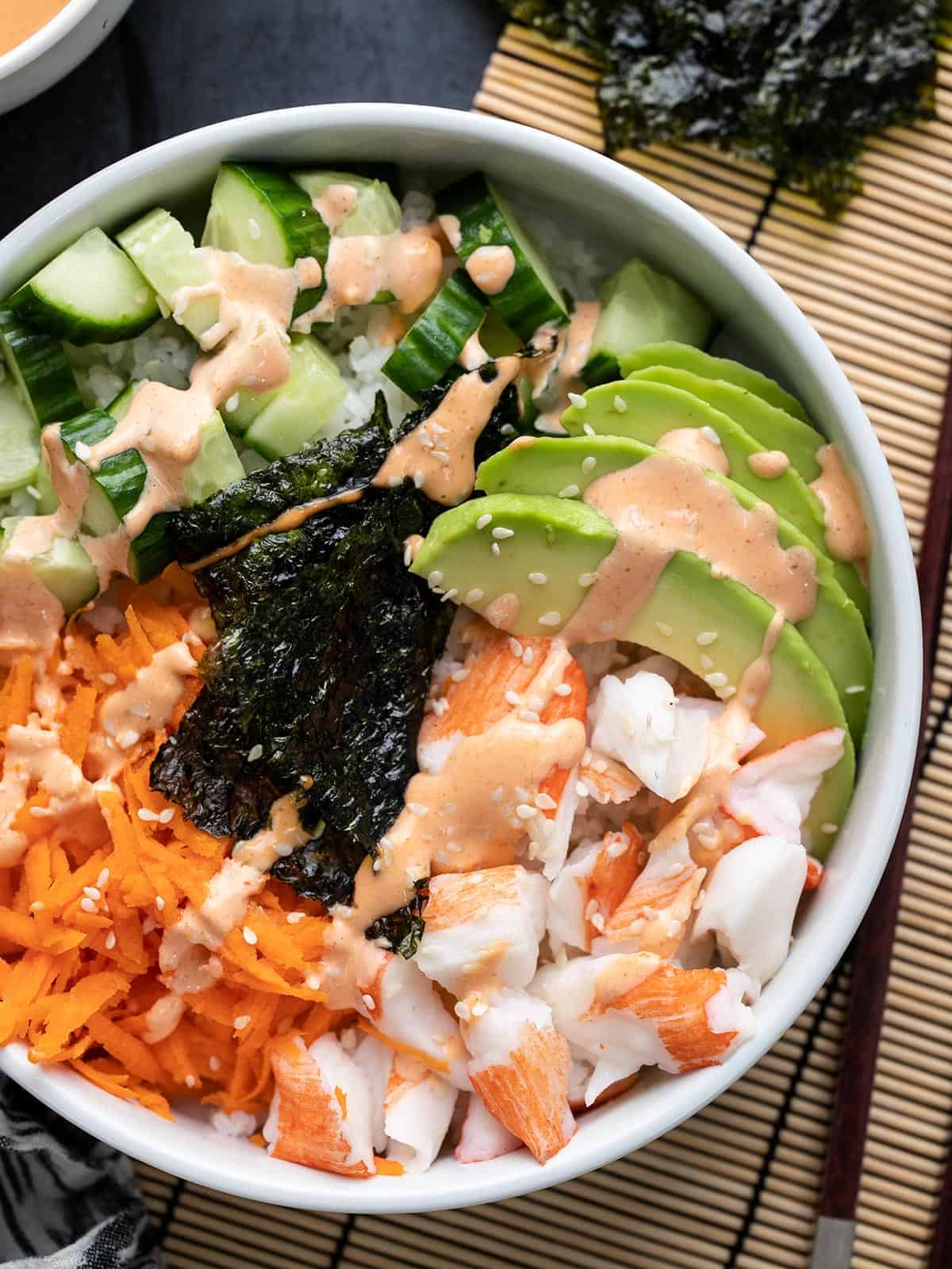 A bowl of Asian salad with carrots and avocado, perfect for those who love imitation crab recipes.