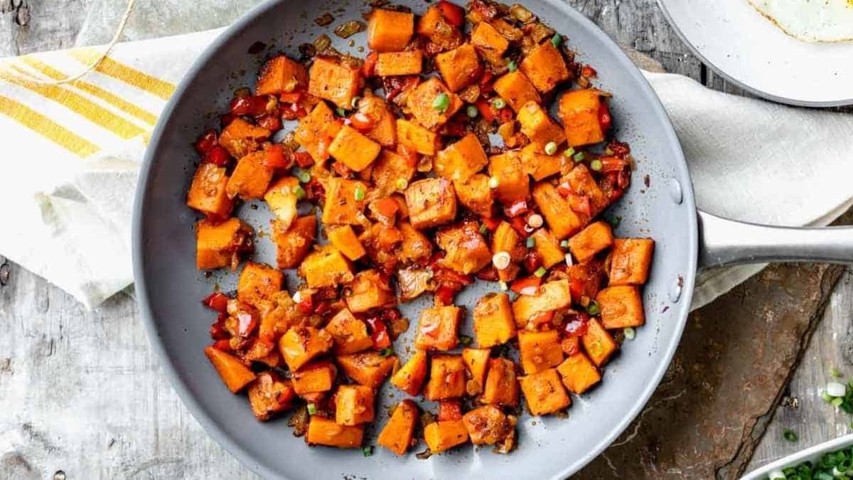 Sweet potatoes in a skillet on a wooden table.