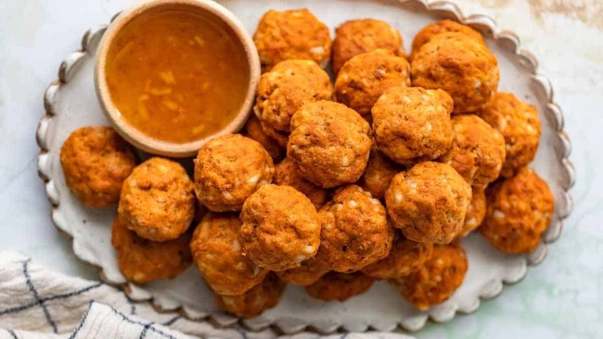Chicken tikka balls on a plate with a bowl of dipping sauce.