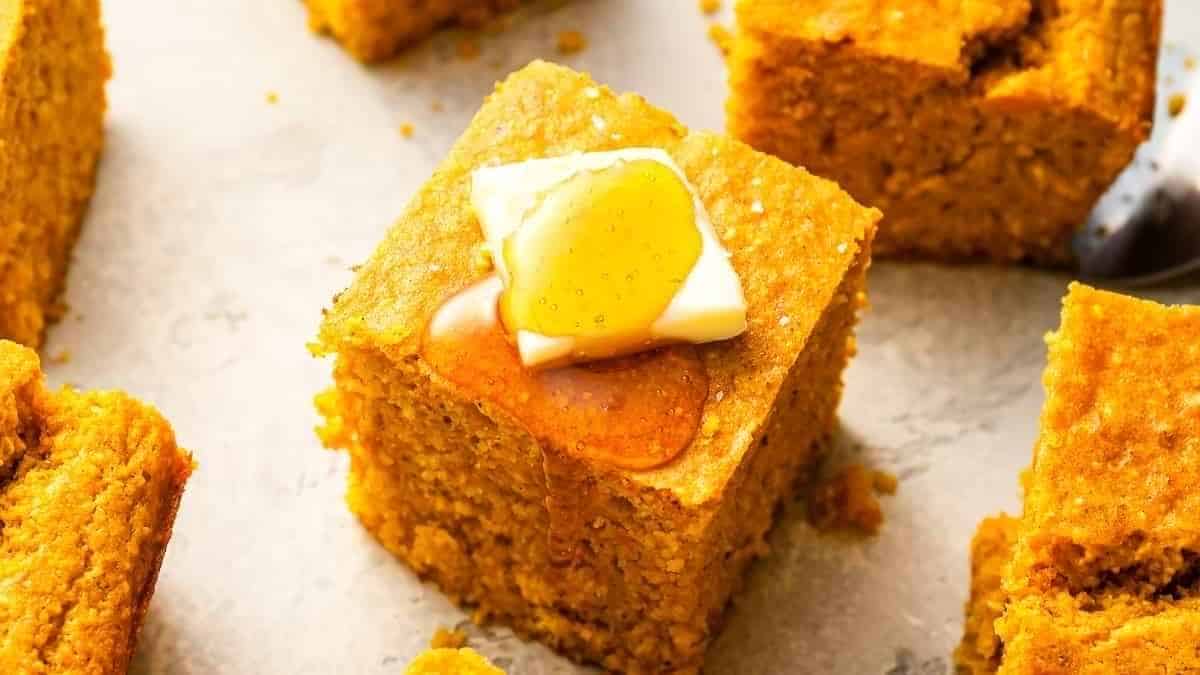A slice of pumpkin bread with butter on top.