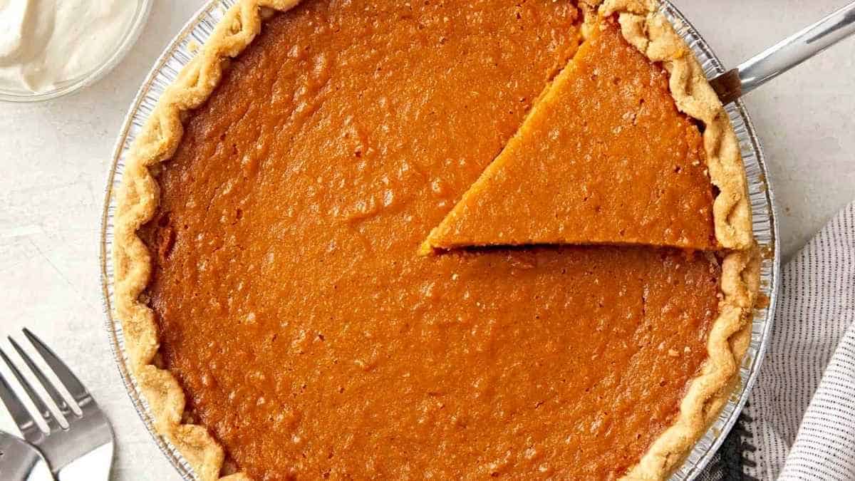 A slice of pumpkin pie in a pan with a fork.