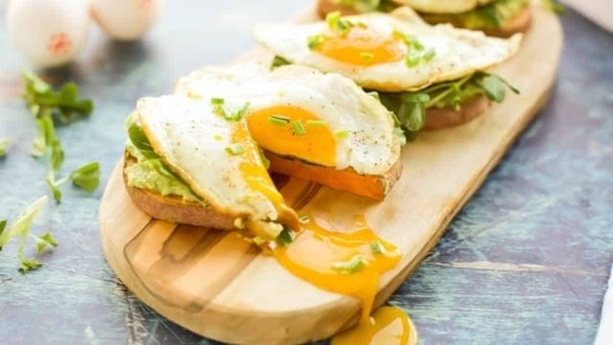 A wooden cutting board with a slice of bread and an egg on it.