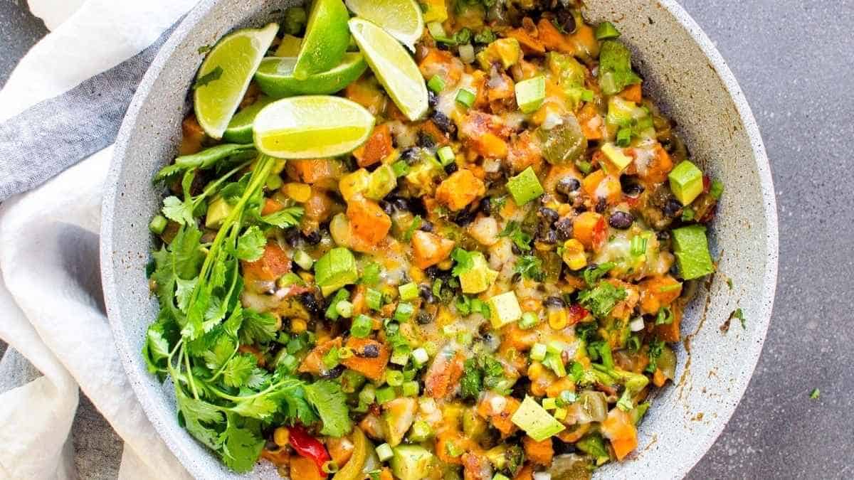 A bowl of mexican black beans and rice with lime wedges.
