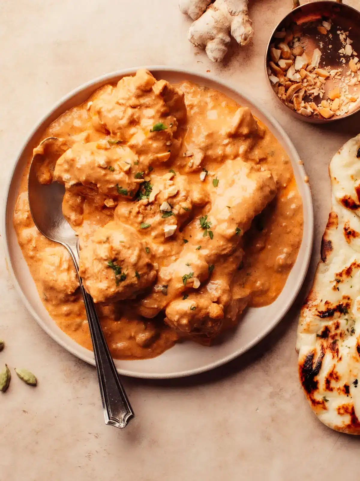 Bone-in chicken tikka masala on a plate with naan bread.