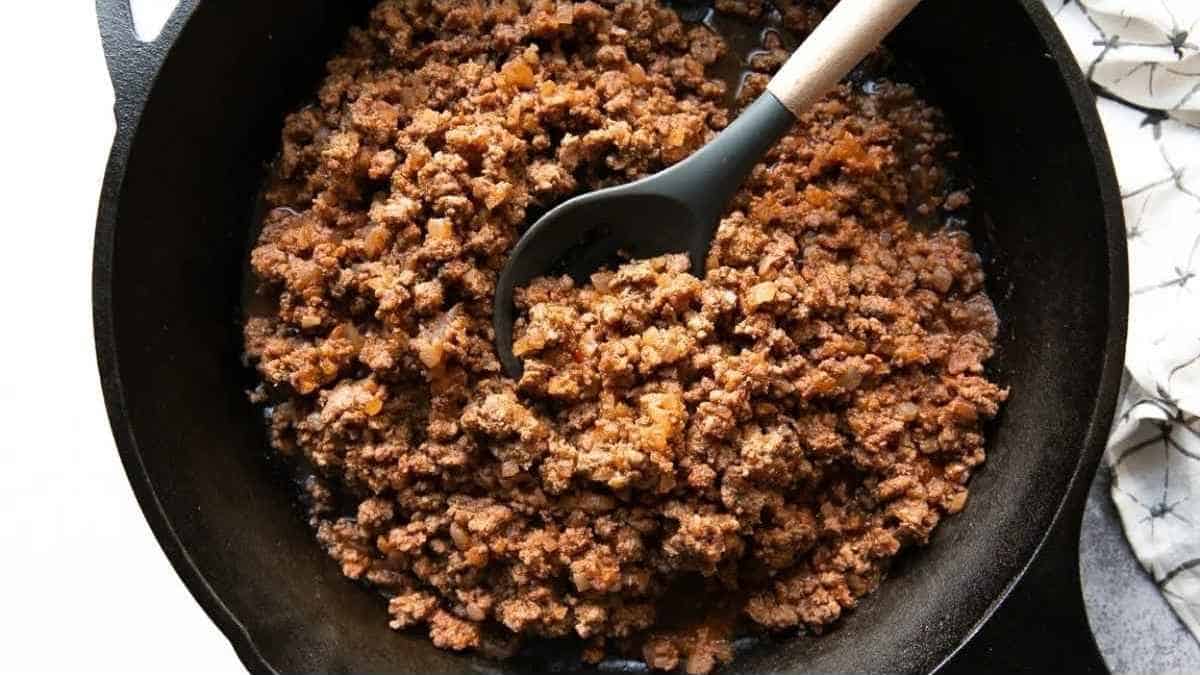 Ground beef in a skillet with a spoon.