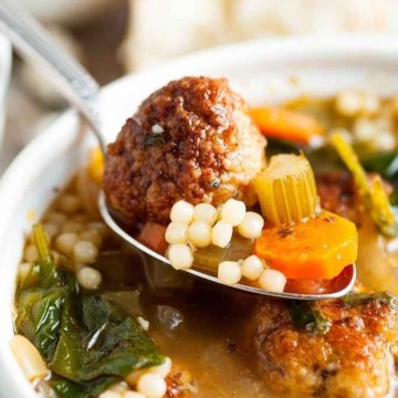 A bowl of soup with meatballs and vegetables.