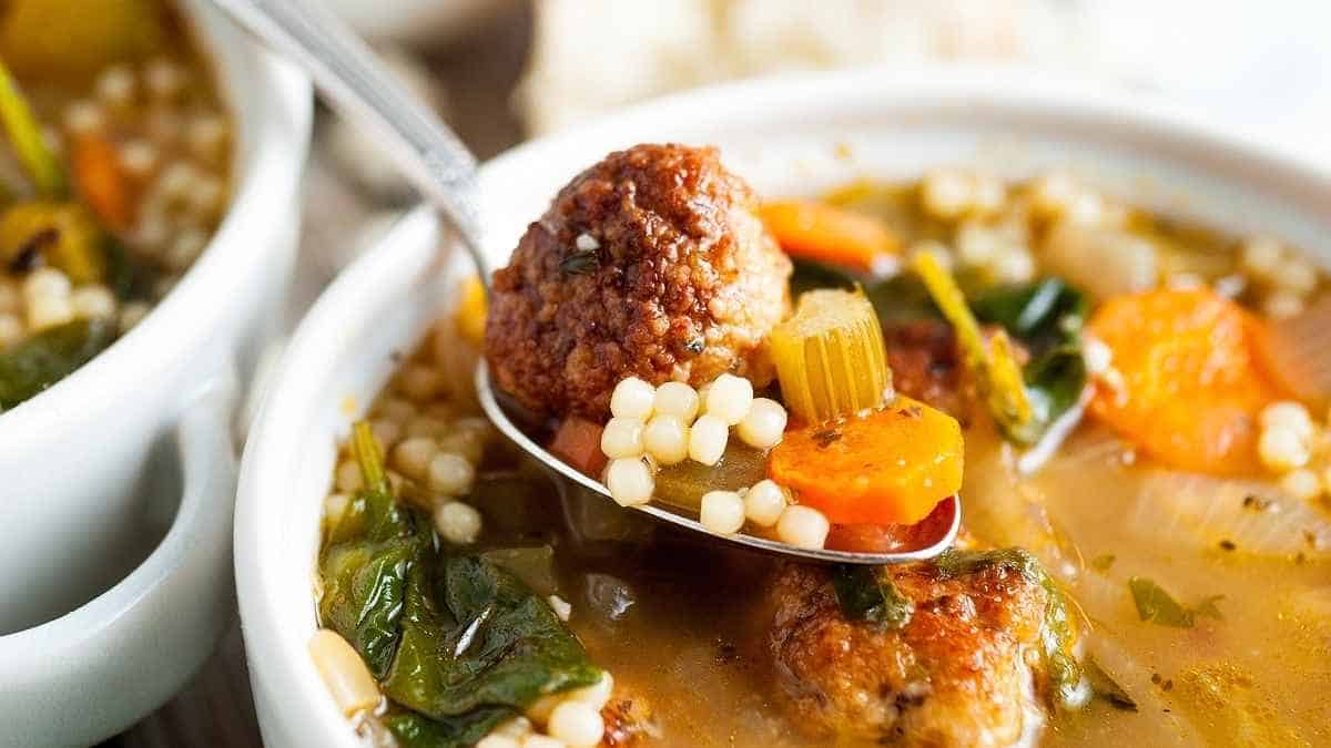 A bowl of soup with meatballs and vegetables.