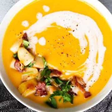 A bowl of sweet potato soup with bacon and sour cream.