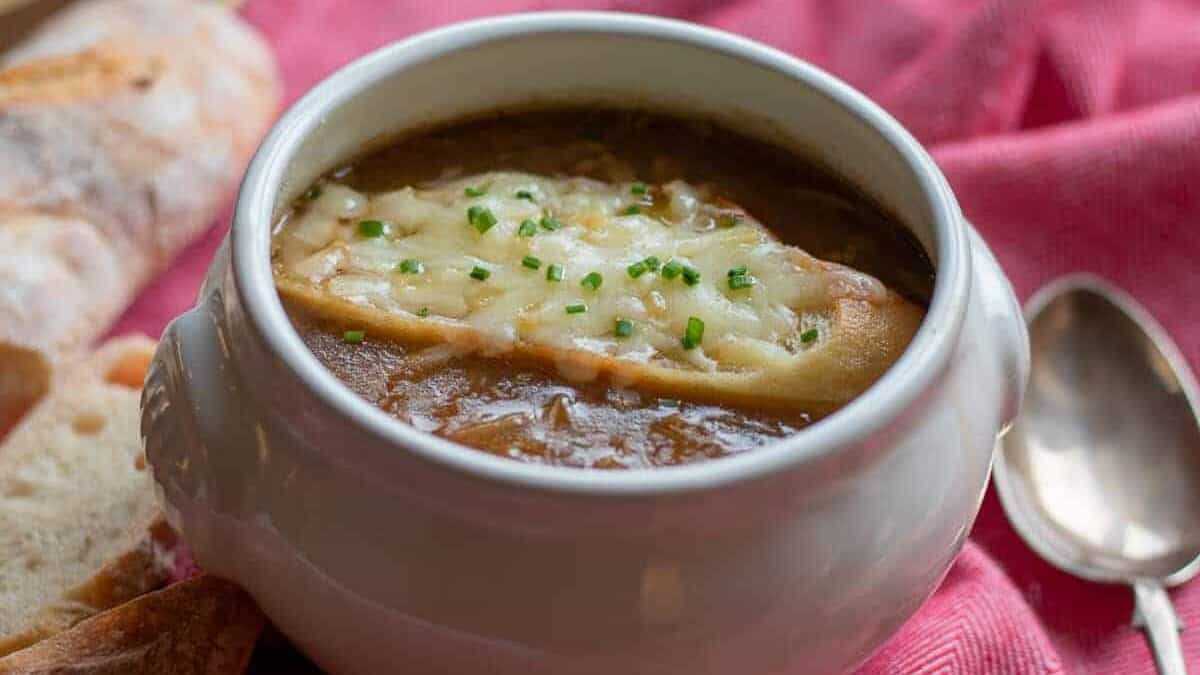 A bowl of soup with bread and cheese.