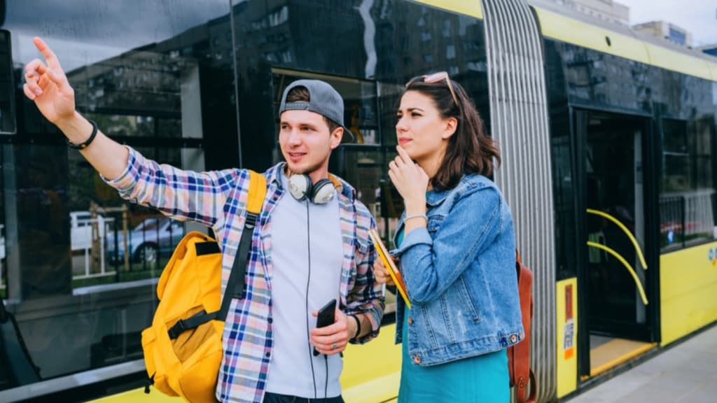 Two young people standing next to a yellow bus.