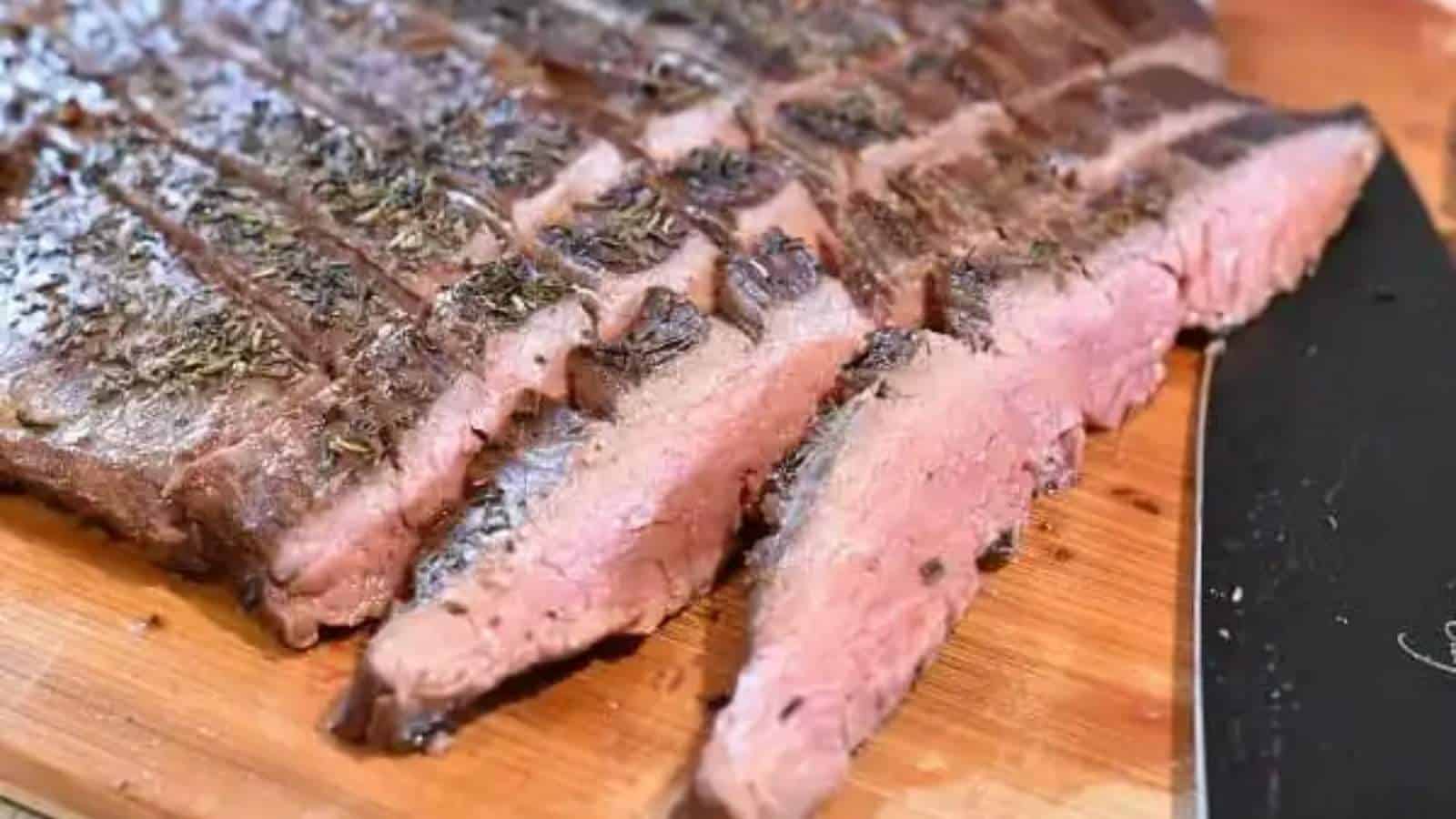 A piece of steak on a cutting board with a knife.
