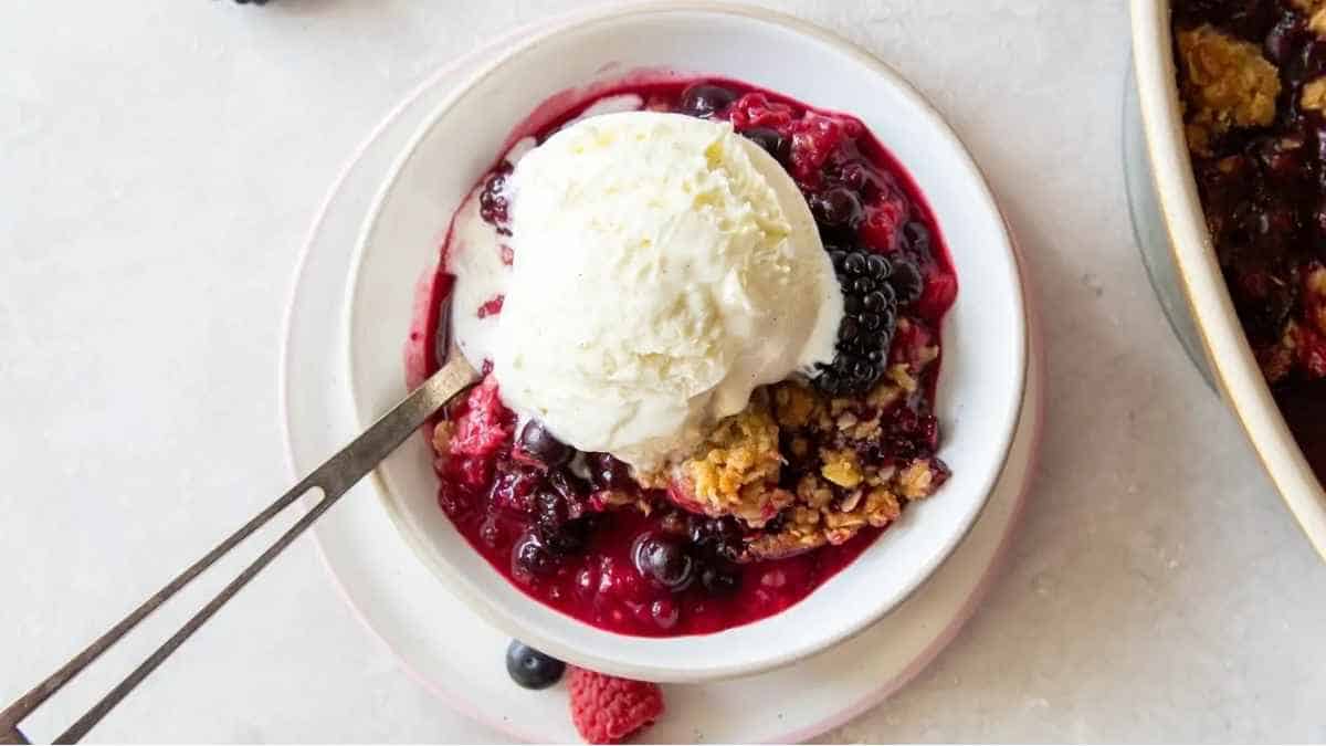 A bowl of berry crisp with a scoop of ice cream.