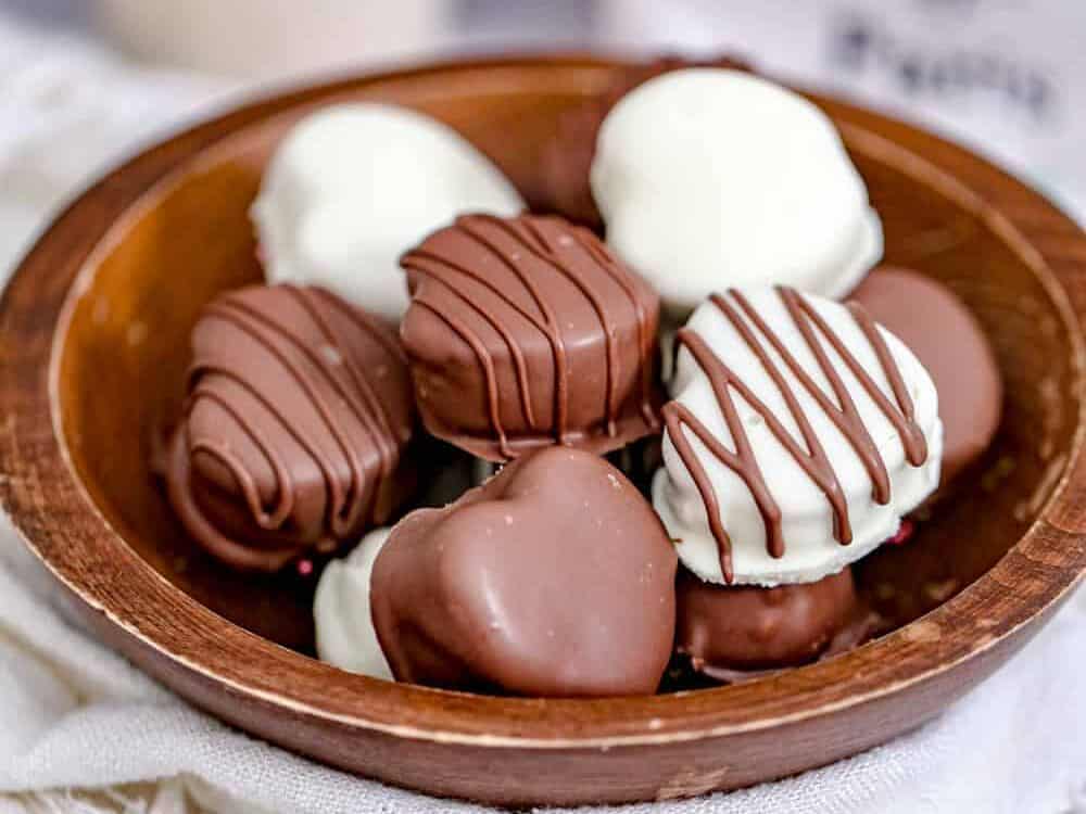Heart shaped chocolates on a wooden plate.